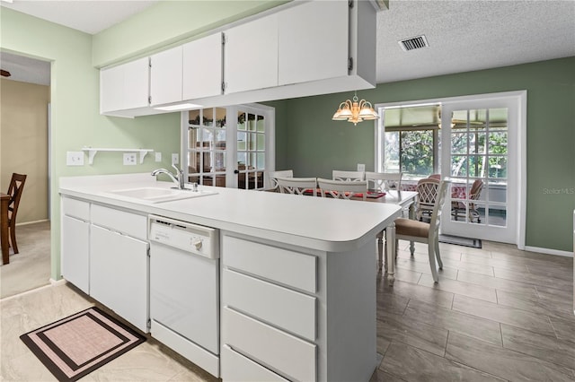 kitchen with light countertops, visible vents, white dishwasher, a sink, and a peninsula