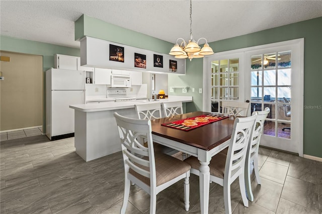 dining room featuring a textured ceiling, baseboards, and a notable chandelier