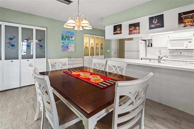 dining room featuring marble finish floor, visible vents, a textured ceiling, and an inviting chandelier