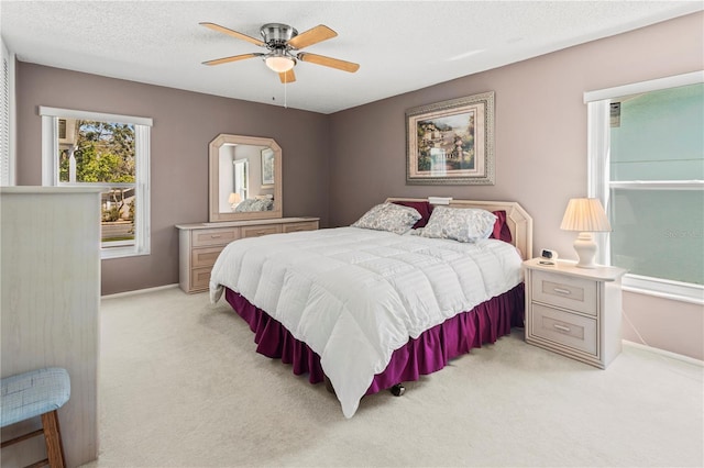 bedroom featuring ceiling fan, a textured ceiling, and light colored carpet