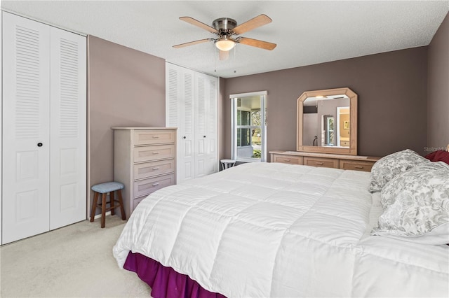 bedroom featuring ceiling fan, two closets, and light colored carpet