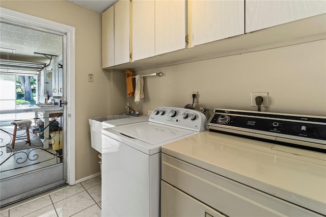 clothes washing area with a textured ceiling, a sink, baseboards, independent washer and dryer, and cabinet space