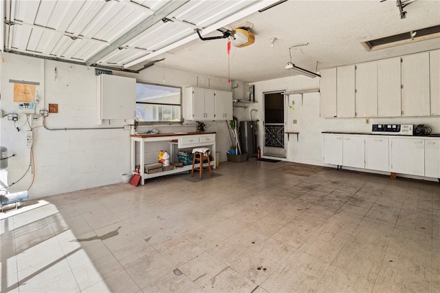 garage with a garage door opener, concrete block wall, and water heater