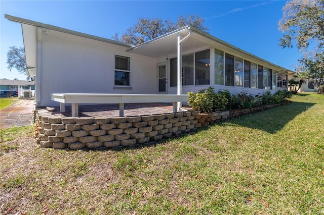 back of house featuring a yard, a sunroom, and stucco siding