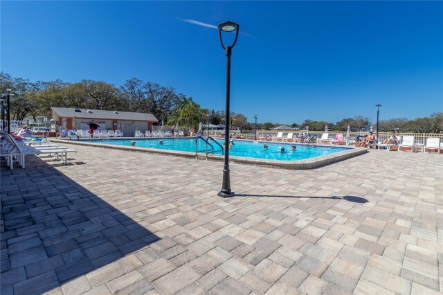 community pool with fence and a patio