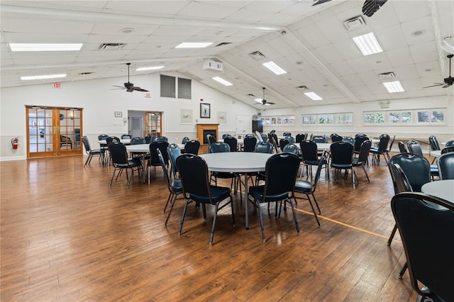 dining area featuring a ceiling fan, visible vents, high vaulted ceiling, and wood finished floors