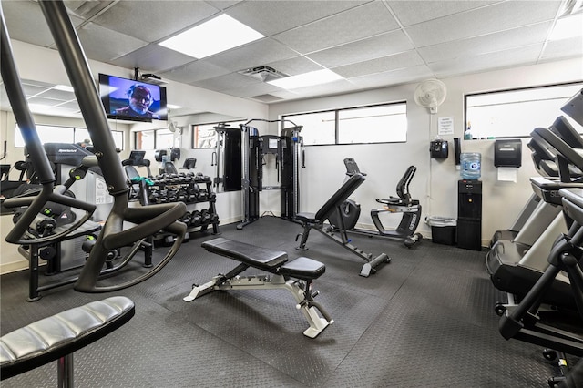 exercise room with a paneled ceiling, baseboards, and visible vents