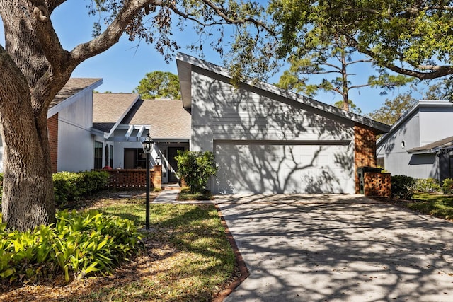 mid-century inspired home featuring a garage, driveway, and brick siding