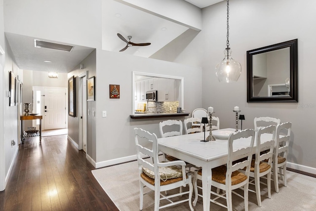 dining area with a ceiling fan, hardwood / wood-style flooring, visible vents, and baseboards