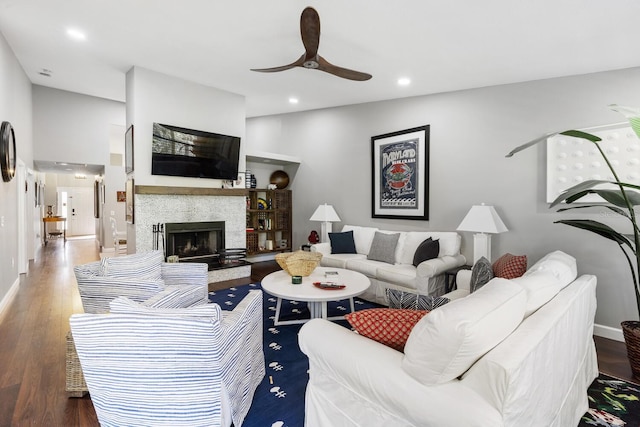 living room featuring recessed lighting, a fireplace with raised hearth, ceiling fan, wood finished floors, and baseboards