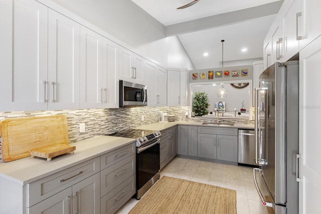 kitchen with tasteful backsplash, appliances with stainless steel finishes, vaulted ceiling with beams, a sink, and light tile patterned flooring