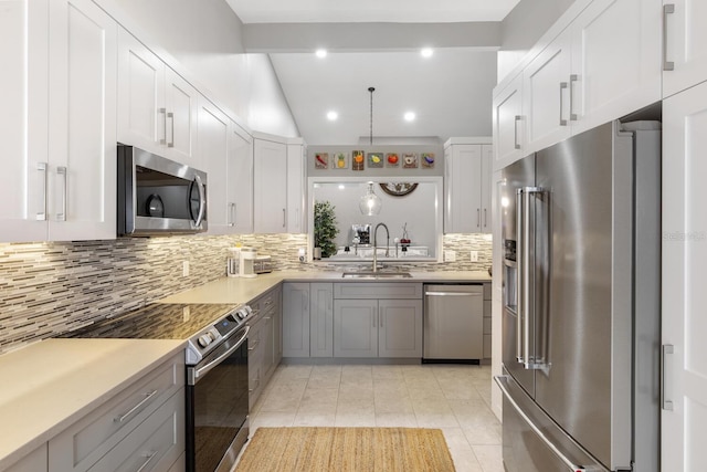 kitchen featuring light tile patterned floors, light countertops, backsplash, appliances with stainless steel finishes, and a sink