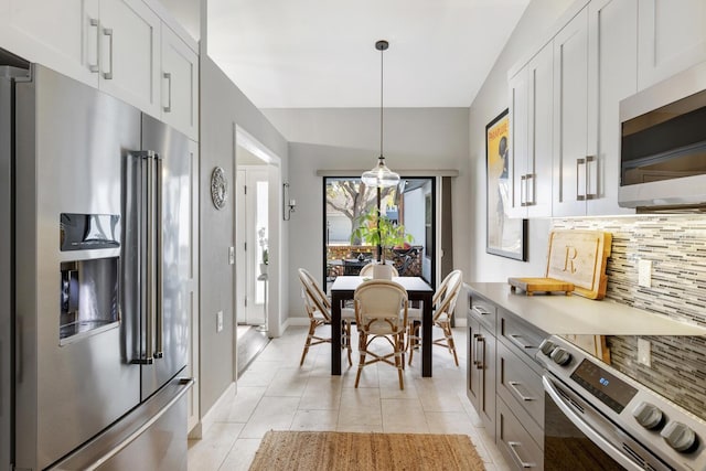 kitchen with decorative light fixtures, light tile patterned floors, stainless steel appliances, light countertops, and decorative backsplash