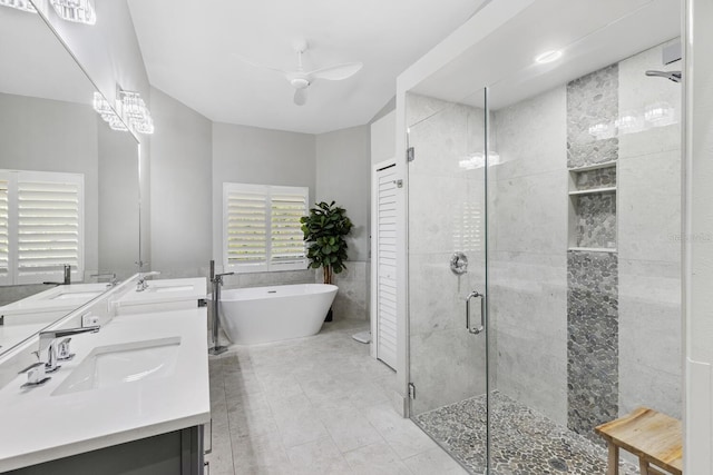 full bathroom with a stall shower, a freestanding tub, a sink, and tile walls