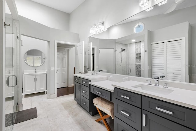 bathroom with a stall shower, two vanities, and a sink