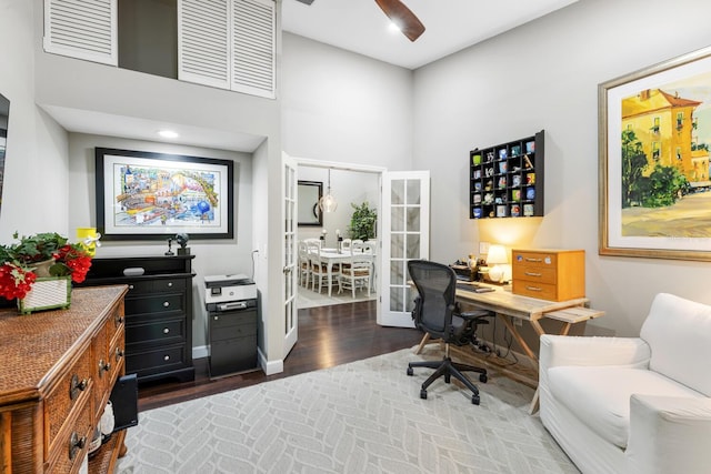 office featuring wood finished floors, a towering ceiling, and baseboards