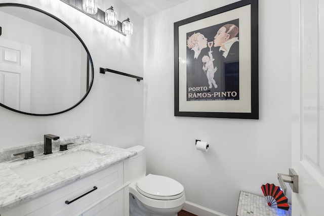 bathroom with toilet, baseboards, and vanity