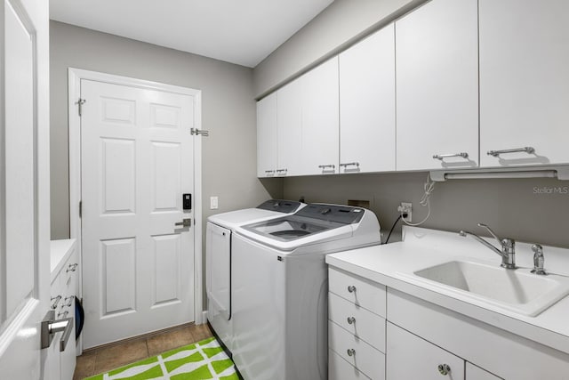 clothes washing area featuring cabinet space, a sink, and washing machine and clothes dryer