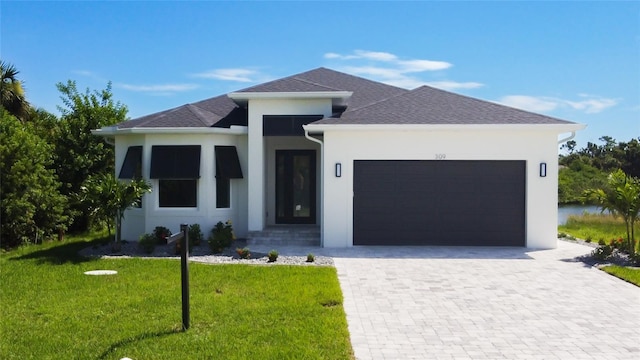 view of front of property featuring a front lawn, decorative driveway, a shingled roof, and an attached garage