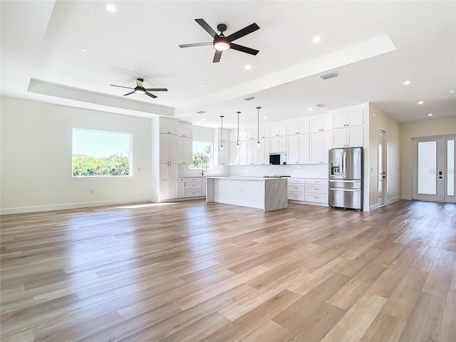 unfurnished living room featuring recessed lighting, a raised ceiling, visible vents, light wood-type flooring, and baseboards