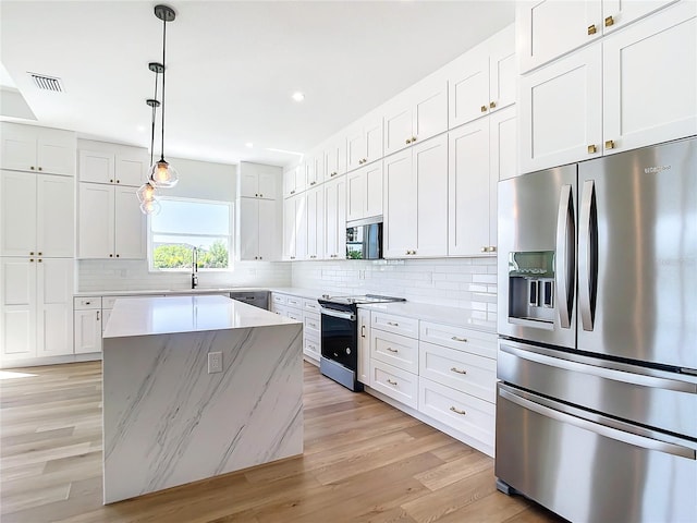 kitchen with decorative backsplash, stainless steel appliances, light wood-type flooring, white cabinetry, and a sink