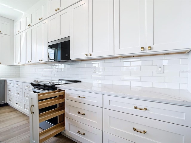 kitchen with light wood-style floors, backsplash, light stone countertops, and white cabinets