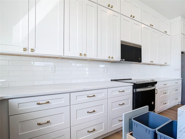 kitchen featuring tasteful backsplash, white cabinets, light wood-style floors, and black / electric stove