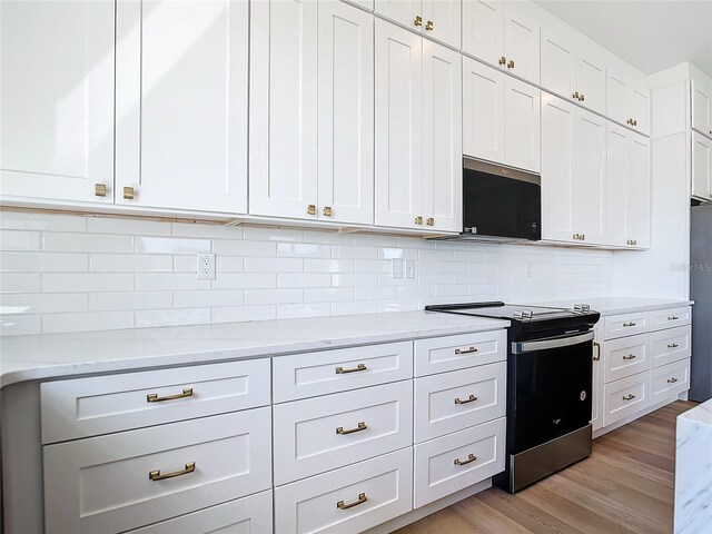 kitchen with light wood-style floors, decorative backsplash, white cabinets, and electric stove