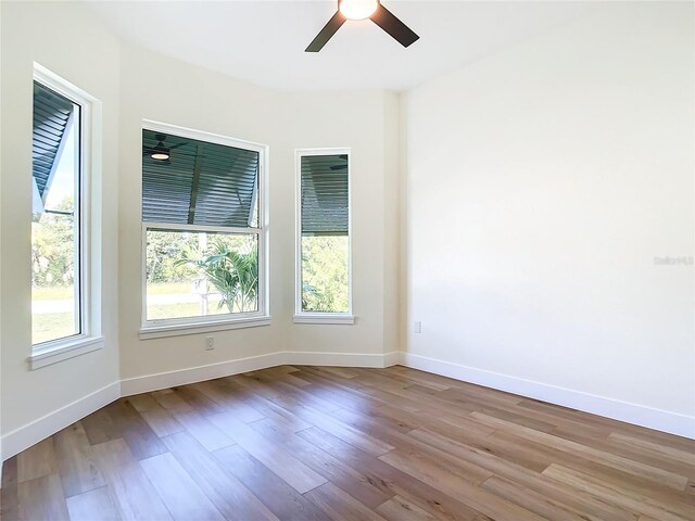 spare room with wood finished floors, a ceiling fan, and baseboards