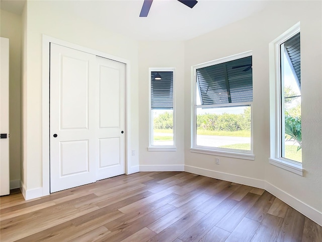 unfurnished bedroom with multiple windows, light wood-style flooring, and baseboards