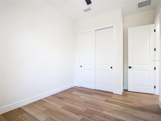 unfurnished bedroom featuring a closet, visible vents, light wood-style flooring, and baseboards