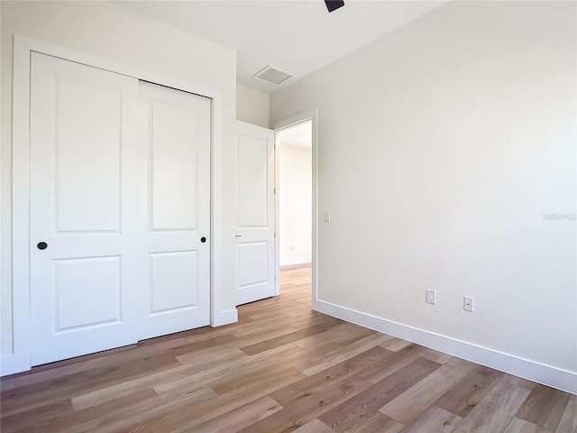 unfurnished bedroom with light wood finished floors, visible vents, baseboards, a ceiling fan, and a closet