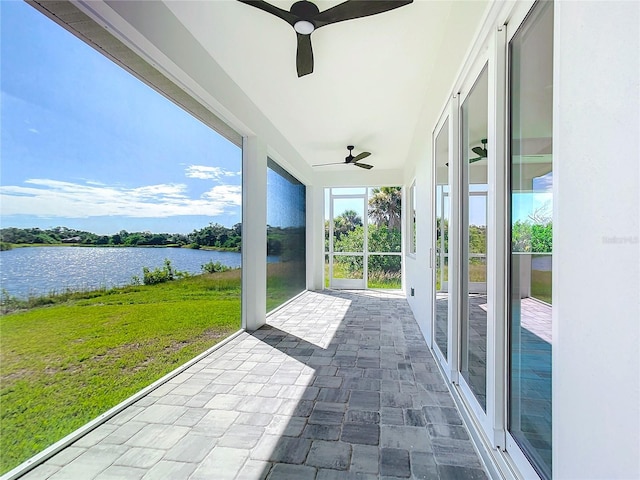 unfurnished sunroom with a water view and ceiling fan