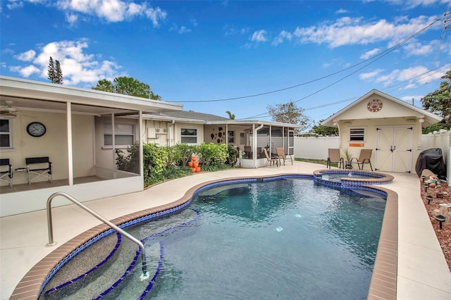 view of swimming pool featuring a pool with connected hot tub, fence, a patio area, a sunroom, and an outbuilding