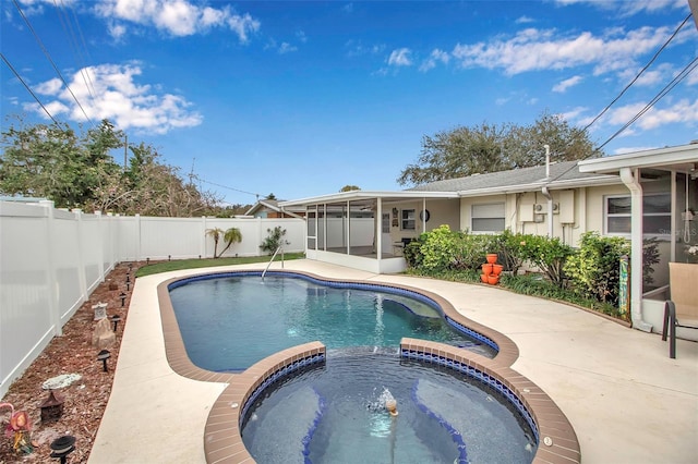 view of swimming pool featuring a patio, a pool with connected hot tub, a fenced backyard, and a sunroom