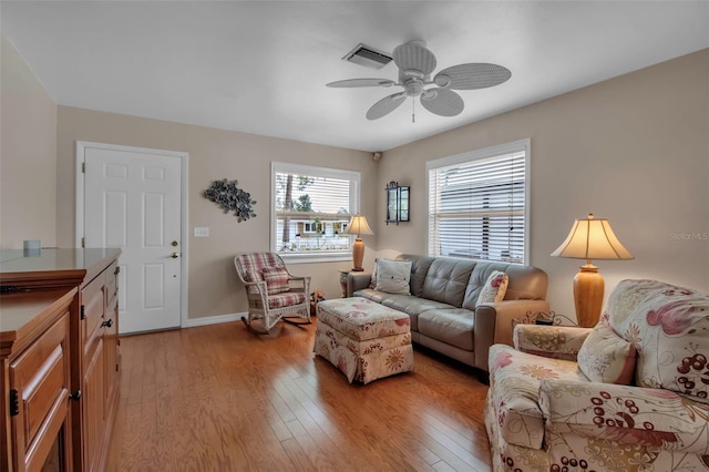 living room featuring visible vents, light wood-style flooring, baseboards, and ceiling fan