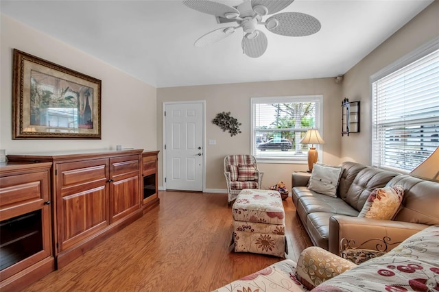 living room featuring light wood finished floors, baseboards, and a ceiling fan