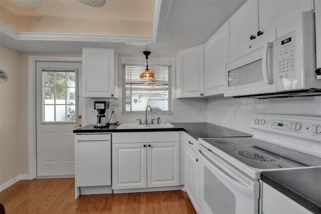 kitchen featuring a sink, white appliances, dark countertops, and light wood-style flooring