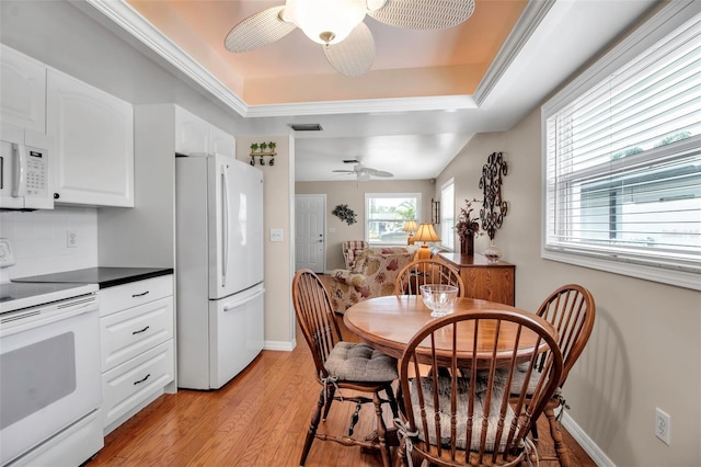 kitchen with visible vents, white appliances, light wood-type flooring, and a tray ceiling