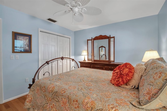 bedroom featuring wood finished floors, visible vents, baseboards, ceiling fan, and a closet