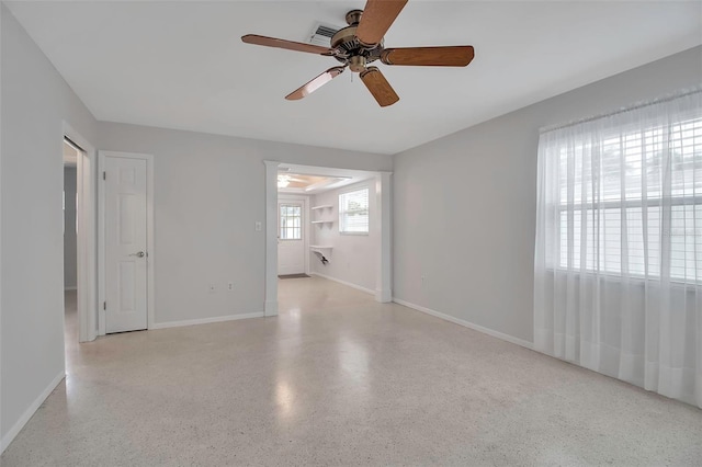 spare room featuring baseboards, light speckled floor, visible vents, and a ceiling fan