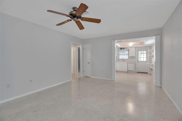 spare room with light speckled floor, a ceiling fan, baseboards, and a sink