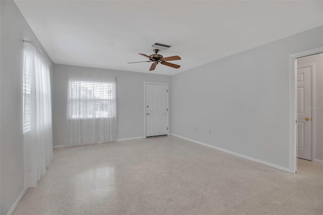 spare room with visible vents, light speckled floor, baseboards, and ceiling fan