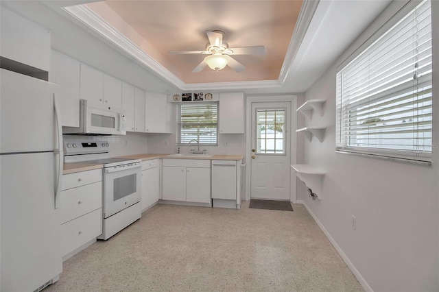 kitchen with white appliances, a sink, light countertops, white cabinetry, and a raised ceiling