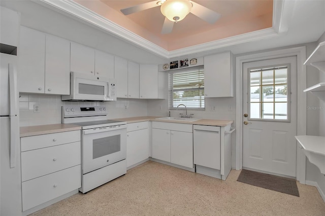 kitchen with a sink, a tray ceiling, white appliances, and white cabinets