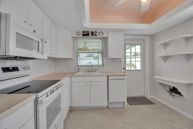 kitchen with a sink, white appliances, white cabinets, light countertops, and a raised ceiling