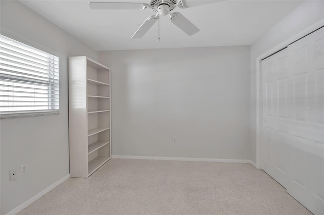 unfurnished bedroom featuring a ceiling fan, light speckled floor, baseboards, and a closet