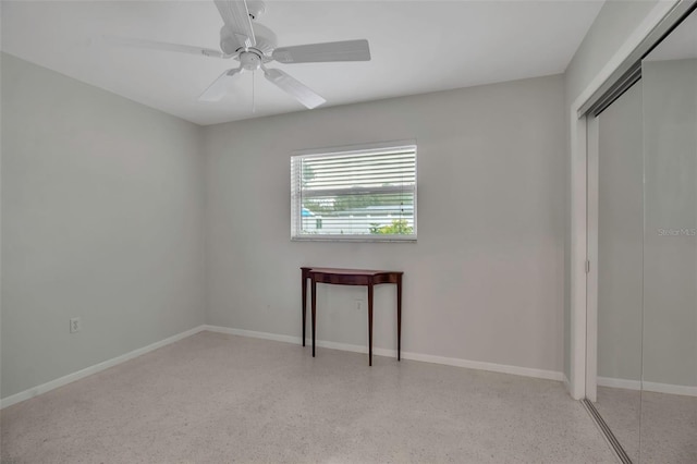 unfurnished bedroom featuring a ceiling fan, light speckled floor, baseboards, and a closet