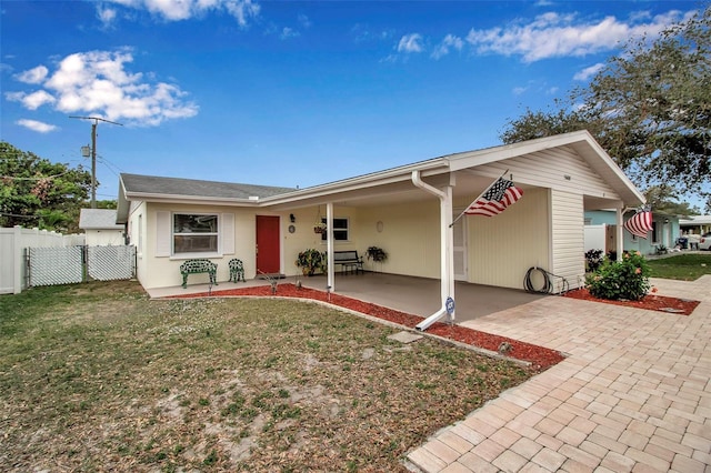 ranch-style home featuring an attached carport, a front yard, and fence