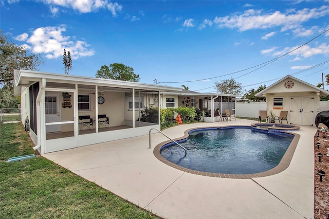 view of pool featuring a pool with connected hot tub, fence, an outdoor structure, a sunroom, and a patio